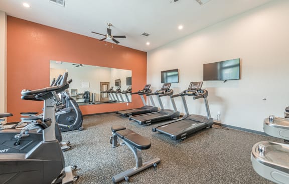 a gym with cardio equipment and a mirror on the wall at Vermillion Apartments, Texas