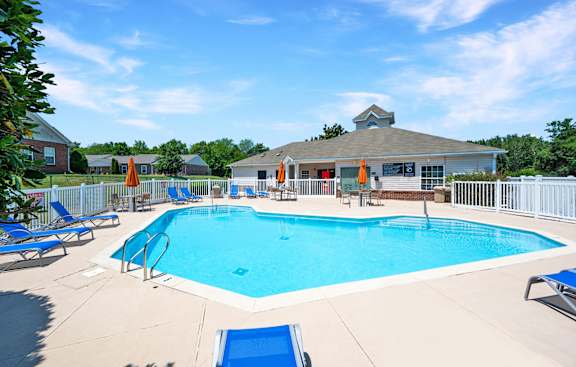 A large outdoor swimming pool with a diving board and lounge chairs.