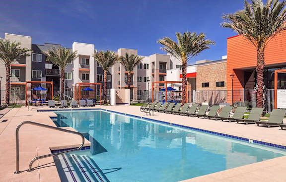 A swimming pool in front of a building with palm trees.