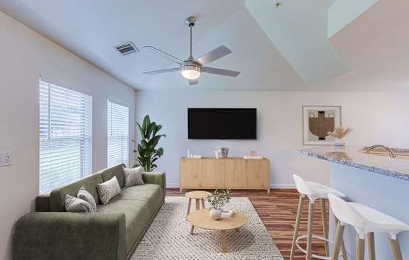 A living room with a green couch, a wooden coffee table, and a flat screen TV mounted on the wall.