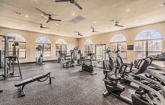a gym with cardio equipment and windows