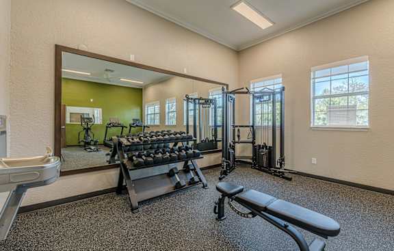 A gym with a mirror, weights, and exercise equipment.