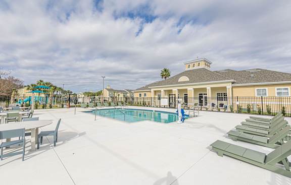 A pool area with sun loungers and a building in the background.
