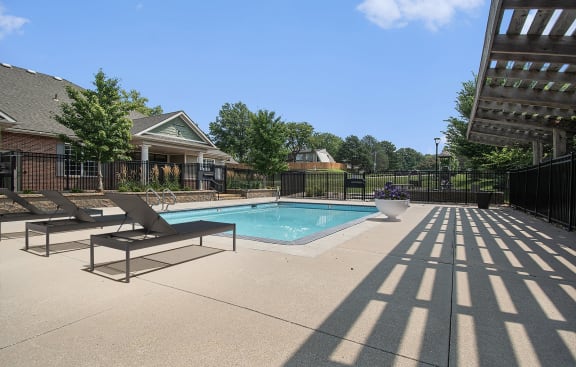 a swimming pool with two lounge chairs in front of a building at Pine Tree Apartments, Omaha, 68114
