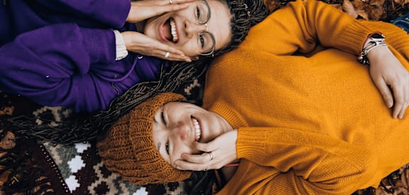 two women laying on the ground with their hands on each other