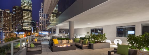 a rendering of the rooftop terrace at night with couches and fire pits