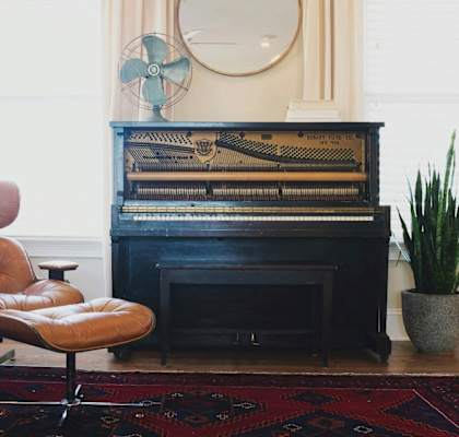 A brown leather chair sits in front of a piano.