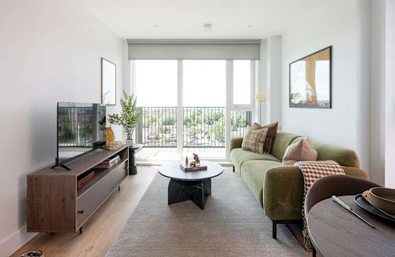 A living room with a green couch and a flat screen TV.