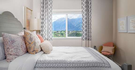 A bedroom with a large bed and a window overlooking a mountain range.