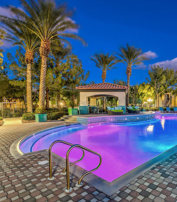 a large swimming pool at night with palm trees at Mirasol Apartments, Nevada, 89119
