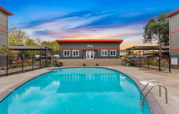 A swimming pool in front of a building with a black fence around it. at The Aviator, Washington, 98055