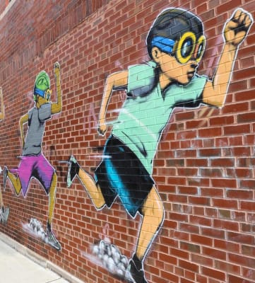 a mural of a boy playing baseball on a brick wall