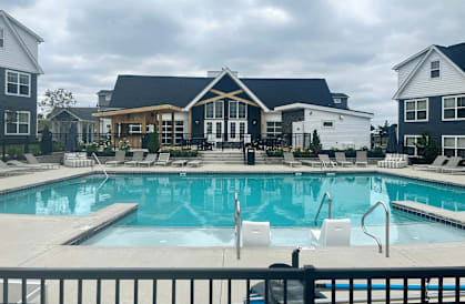 a large swimming pool with lounge chairs and a building in the background