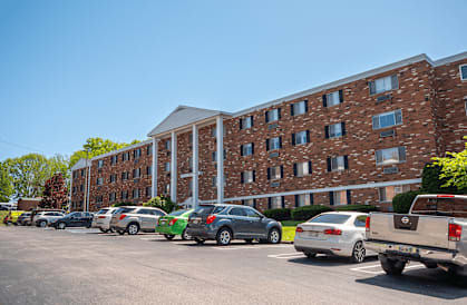 A parking lot with cars and a brick building in the background.