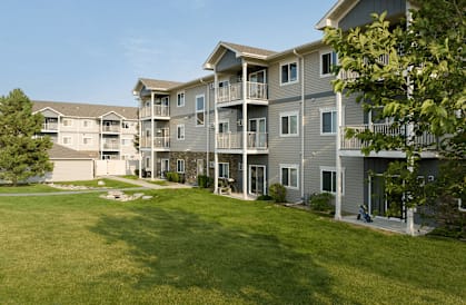 Apartment complex with green lawns and trees.