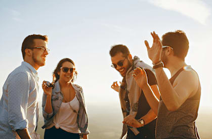 Four friends are standing together and enjoying the sunset.