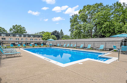 a swimming pool with blue chaise lounge chairs and a building in the background