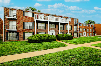 A red brick apartment building with a white balcony on the second floor.
