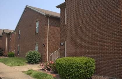 a brick building with a staircase and bushes in front of it