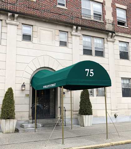 a green awning with the number 75 on it in front of a white building