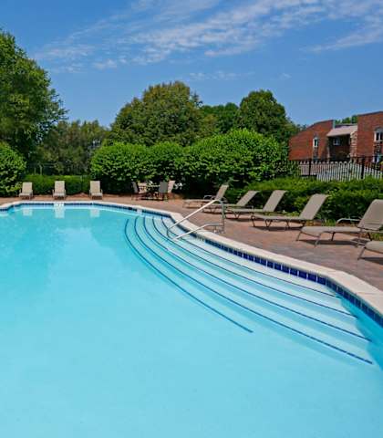 a swimming pool with chaise lounge chairs and trees in the background