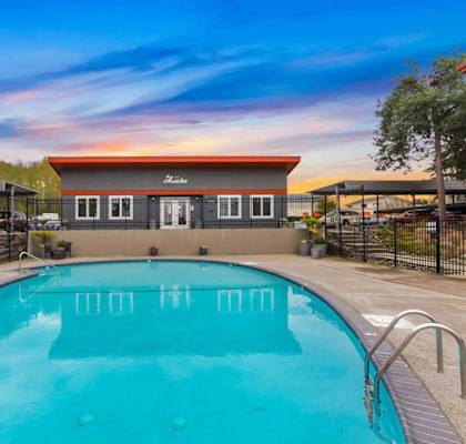 A swimming pool in front of a building with a black fence around it.