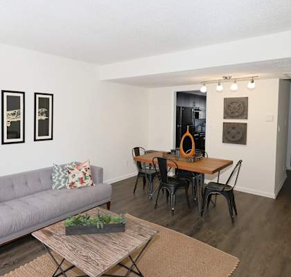 A living room with a grey couch, a coffee table, and a dining table with chairs.