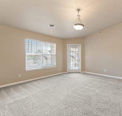 A spacious room with a carpeted floor and a chandelier hanging from the ceiling.
