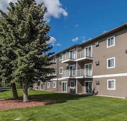 A large apartment building with a tree in front of it.