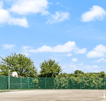 a tennis court in front of trees and a blue sky