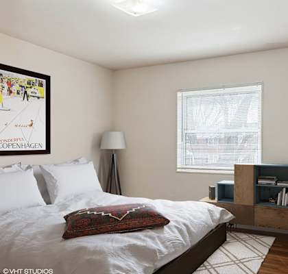a bedroom with a bed and a dresser in front of a window