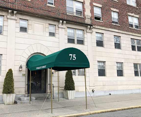 a green awning with the number 75 on it in front of a white building