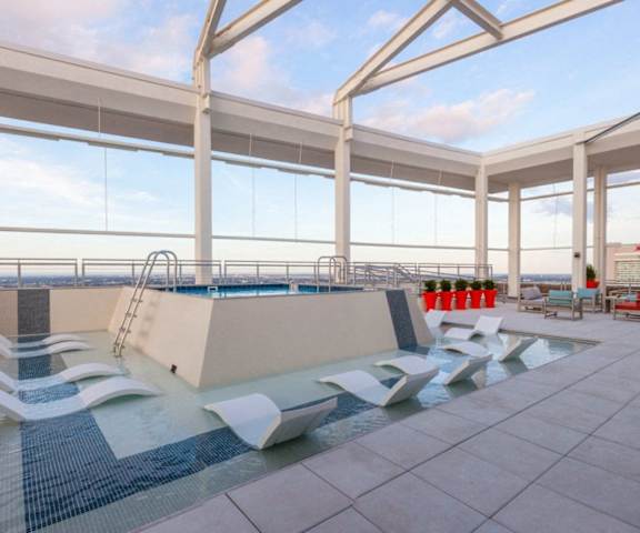 a pool on the roof of a building with lounge chairs and a large window