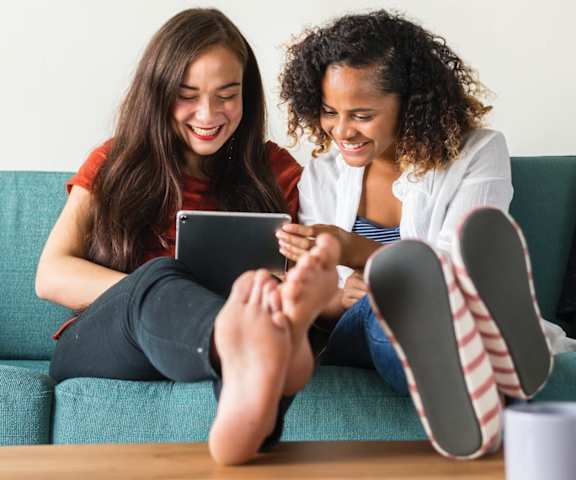 two friends sitting together on a sofa in apartment home
