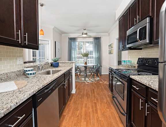 A kitchen with dark wood cabinets and granite countertops.
