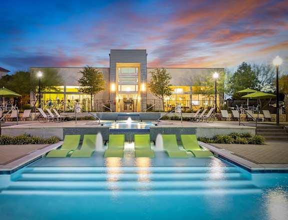 a swimming pool at night with a building in the background