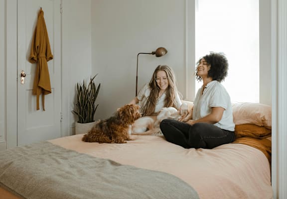 two people sitting on a bed with a dog