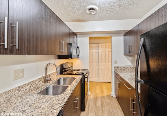 apartment kitchen with granite counter tops and black appliances