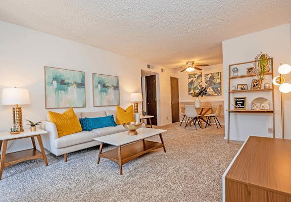 a living room with a white couch and yellow and blue pillows