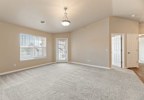 A spacious room with a carpeted floor and a chandelier hanging from the ceiling.