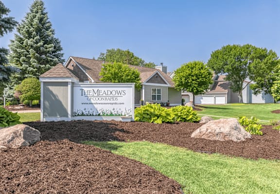 A sign for The Meadows subdivision stands in front of a house.