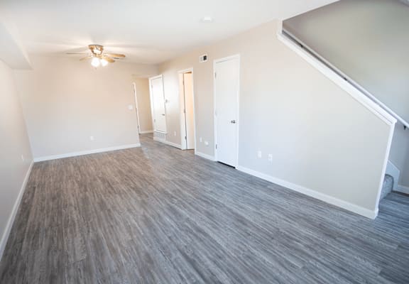 A room with a grey carpet and a ceiling fan.