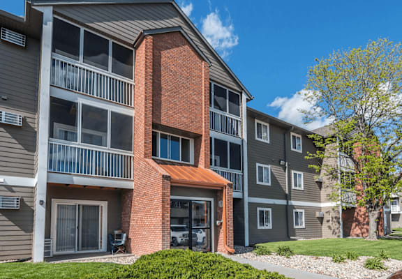 A modern apartment building with a red brick chimney and balconies.