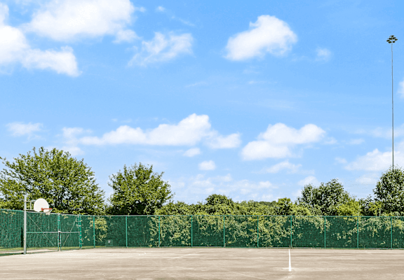 a tennis court in front of trees and a blue sky