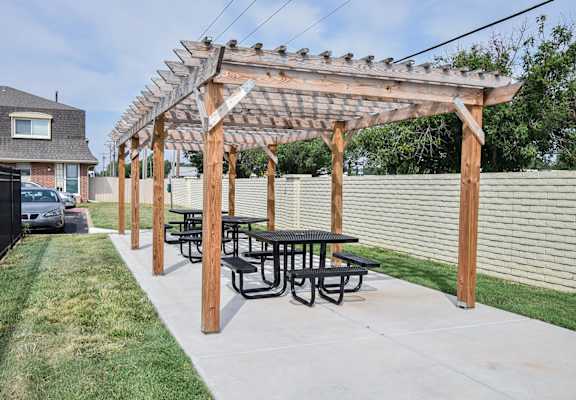 a picnic table under a wooden pergola in a backyard