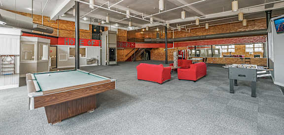 A room with a pool table and a foosball table.