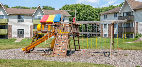 A playground with a yellow slide and a wooden structure.