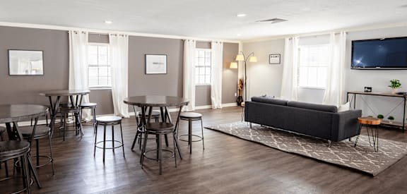 A living room with a grey couch, a television, and a dining table with chairs.