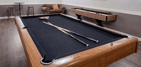 A pool table in a room with a couch and a painting on the wall.