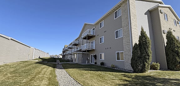 A residential building with a grassy front yard and a stone pathway.